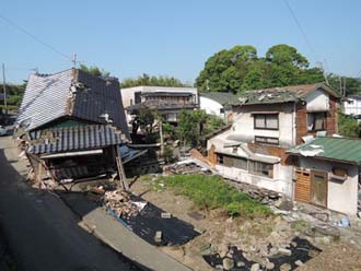 傾いてしまったお住まいと屋根が被害を受けたお住まいが並んでいる