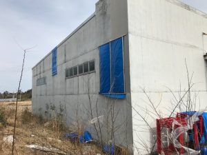 強風の影響で外壁材が一部剥がれた倉庫